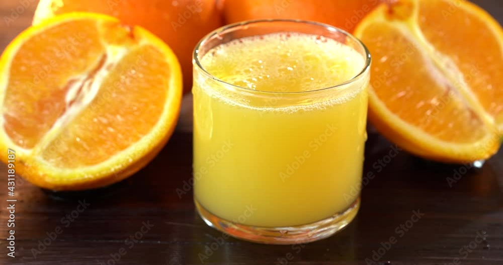 4k Shot of Pouring Fresh Orange Juice into Glass. Oranges are on the black wood table 4k Shot of Pouring Fresh Orange Juice into Glass. Oranges are on the black wood table