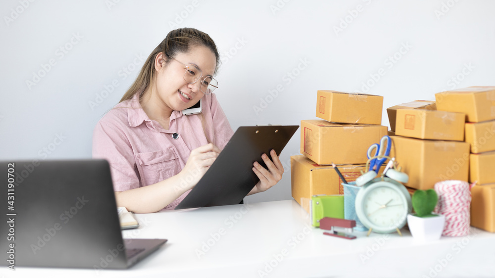 Young woman selling products online was talking on the phone to receive an order from a customer who called and wrote down the list in a notebook, New kind of business for young, Sell online. Young woman selling products online was talking on the phone to receive an order from a customer who called and wrote down the list in a notebook, New kind of business for young, Sell online.