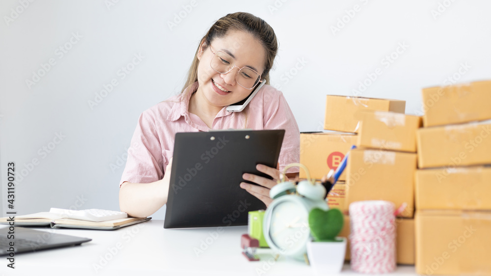 Young woman selling products online was talking on the phone to receive an order from a customer who called and wrote down the list in a notebook, New kind of business for young, Sell online. Young woman selling products online was talking on the phone to receive an order from a customer who called and wrote down the list in a notebook, New kind of business for young, Sell online.