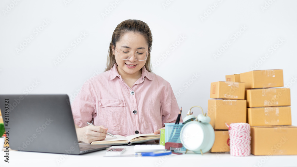 Young Asian woman is writing down the customer's details and addresses on the Clipboard in order to prepare for shipping according to the information, New kind of business for young, Sell online. Young Asian woman is writing down the customer's details and addresses on the Clipboard in order to prepare for shipping according to the information, New kind of business for young, Sell online.