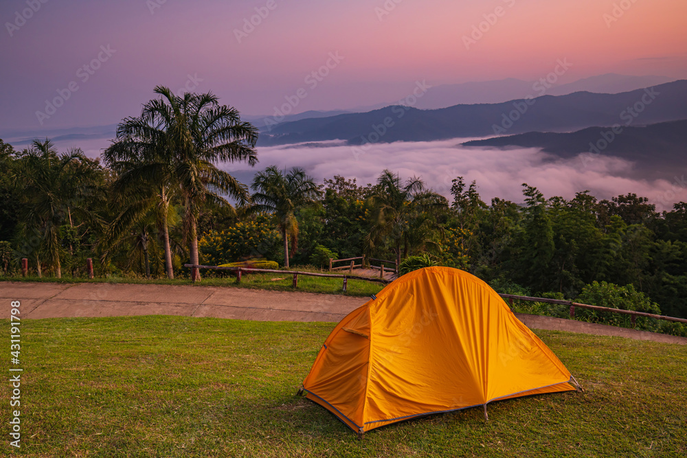 The orange hiker's  tent on the grass fieid in  high mountain at Sri-Nan National park, Nan province Thailand.