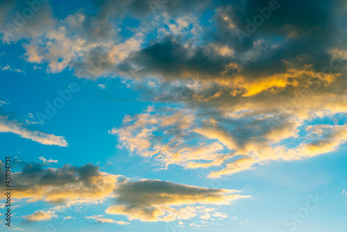 Yellow-gray clouds on a blue sky in the evening at sunset.