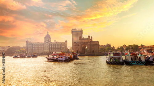 Sunset photo of city scape with The Gateway of India along with Taj and boats as seen from the Mumbai Harbour in Mumbai, Maharashtra India  with a beautiful warm sky. © Sanjeev