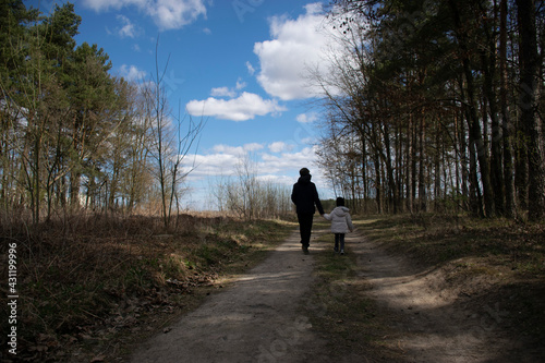 a boy and a girl are walking through the forest park on a spring sunny day