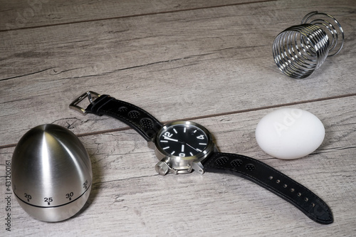 Wrist watch, egg and chronometer on a wooden background. Kitchen alarm clock. Morning. Fast Breakfast 