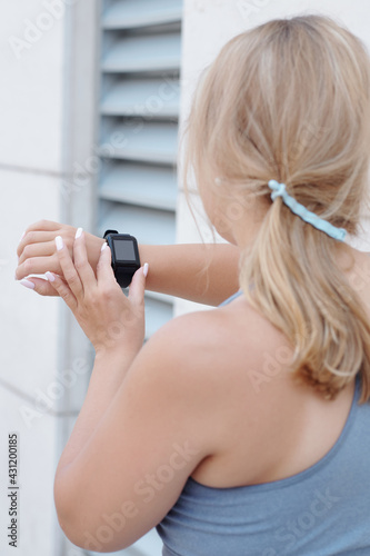 Plus size young woman checking heart rate on her smartwatch after training or jogging outdoors