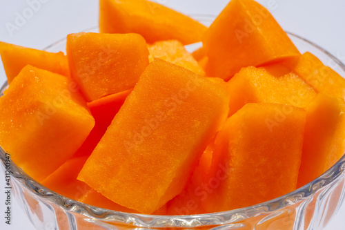 Close up of Cantaloupe fresh melon cubes in glass bowl on beige background. Organic vegetarian healthy food. Diet dessert fruit.