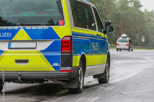 Partial view of a German police car on the highway in rainy weather. Passenger side of the vehicle with the lettering Police on the body in blue and yellow paintwork