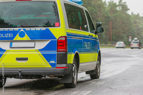 side view of the German police car. Passenger side of the vehicle on the motorway in rainy weather with the lettering Police on the body in blue and yellow paintwork
