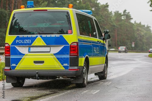 Police car in an emergency stop next to the motorway from the state of Brandenburg. Police vehicle in blue and yellow paintwork with reflective strips. Police lettering on the body