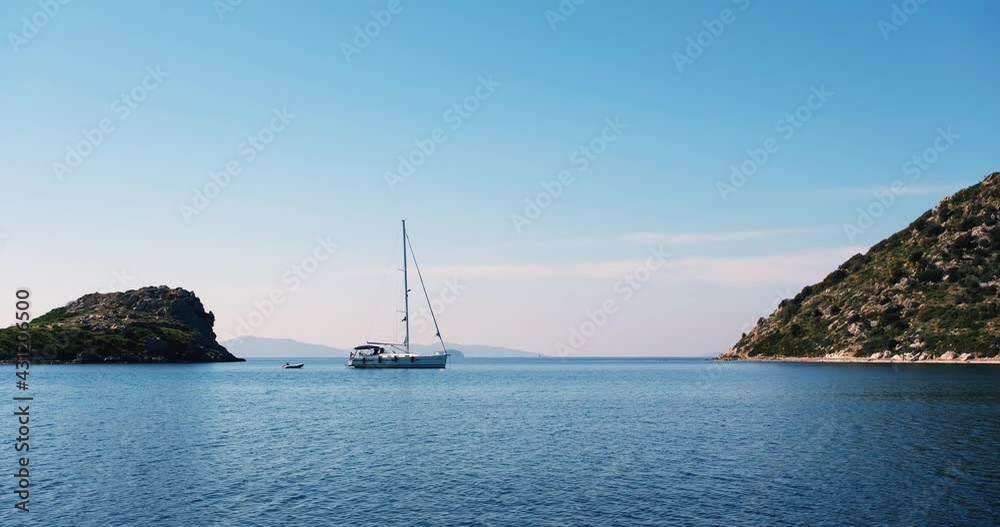 A single sailing boat moored in the middle of a bay on tranquil waters. Blue sea and sky. Surrounded by islands. Natural 4k resolution background with copy space. Romantic vacation escape. Silence A single sailing boat moored in the middle of a bay on tranquil waters. Blue sea and sky. Surrounded by islands. Natural 4k resolution background with copy space. Romantic vacation escape. Silence
