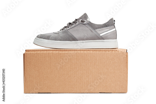 Grey casual sports shoes/sneaker on a brown cardboard box isolated on a white