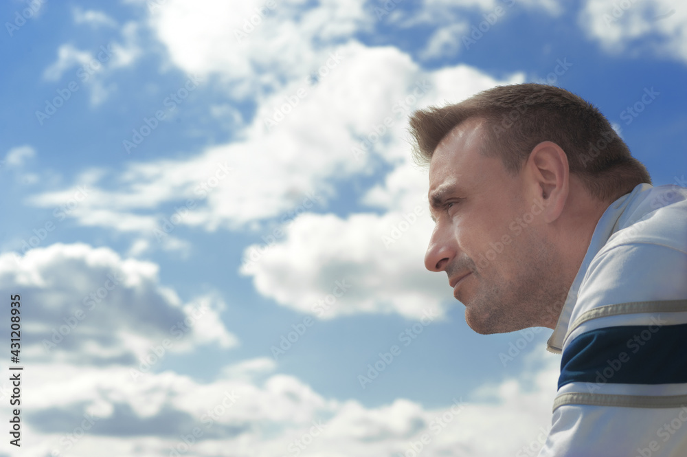 An attractive adult Caucasian man looking to the horizon with the sky unfocused in the background. Foreground An attractive adult Caucasian man looking to the horizon with the sky unfocused in the background. Foreground