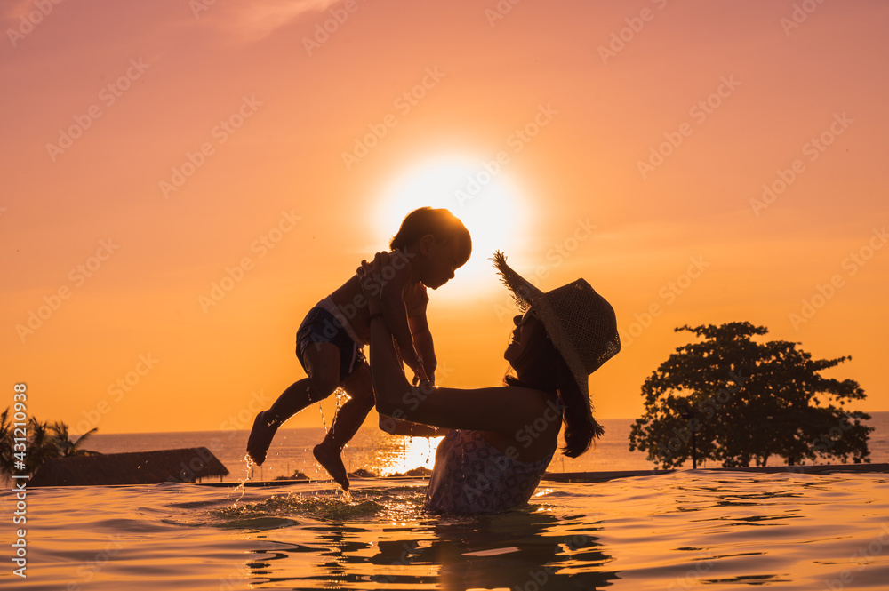Asian mother and little son enjoying swimming in a swimming pool in summer vacation.