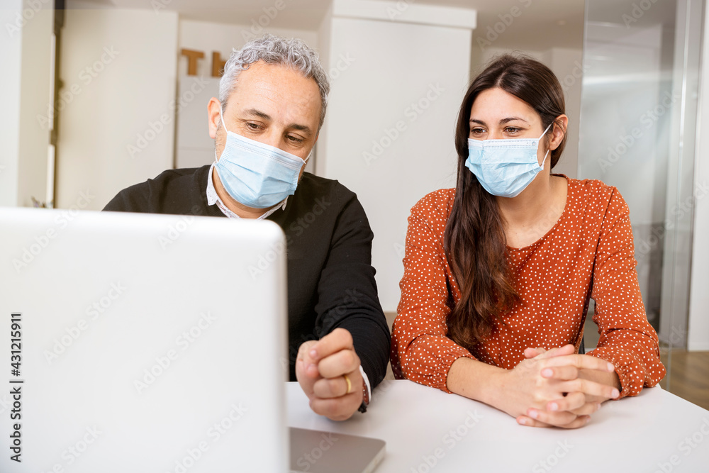 Business Couple Wearing Masks Using Laptop.