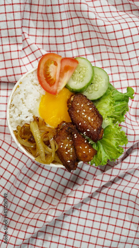 Healthy fresh rice bowl with tomato green cuisine and fried chicken wings on red squared cloth
