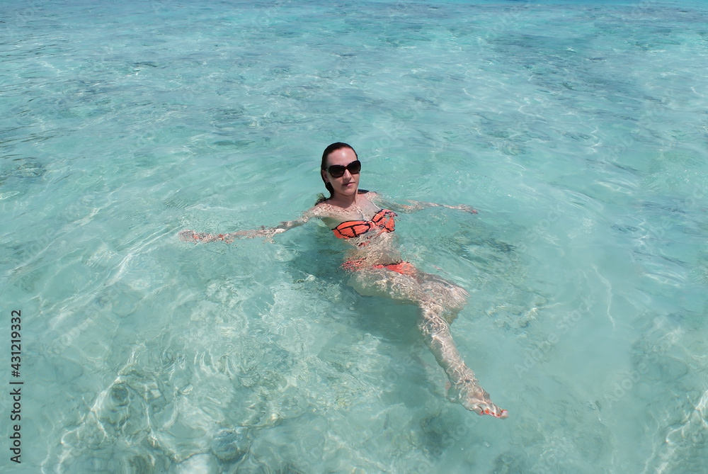 A young woman is resting and swimming in the ocean on a paradise island.