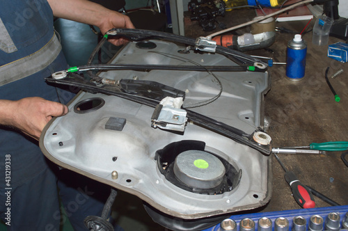 A mechanic holds a car door panel in his hands