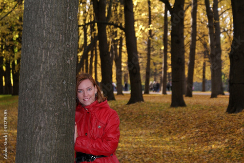 A girl stands near a tree against the background of fallen autumn foliage © Elena Shap