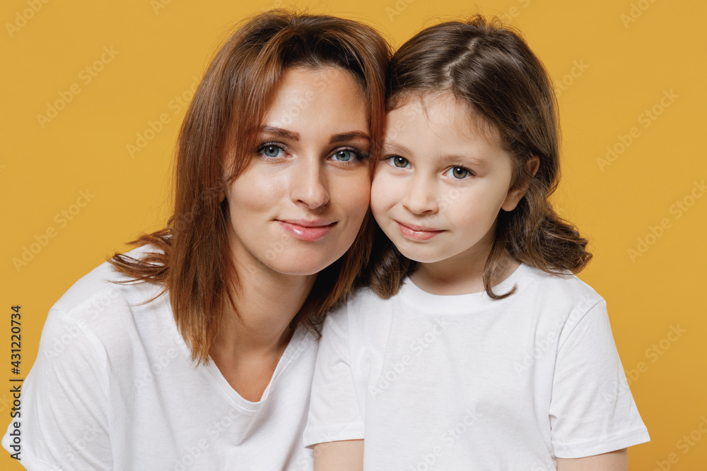 Happy calm woman in basic white t-shirt have fun with cute child baby girl 5-6 years old. Mommy little kid daughter isolated on yellow orange color background studio. Mother's Day love family concept. Happy calm woman in basic white t-shirt have fun with cute child baby girl 5-6 years old. Mommy little kid daughter isolated on yellow orange color background studio. Mother's Day love family concept.
