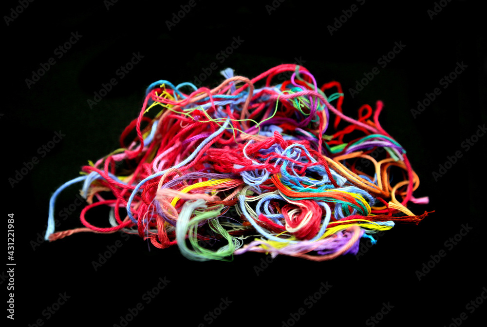 Ball of multicolored tangled threads for needlework on black background