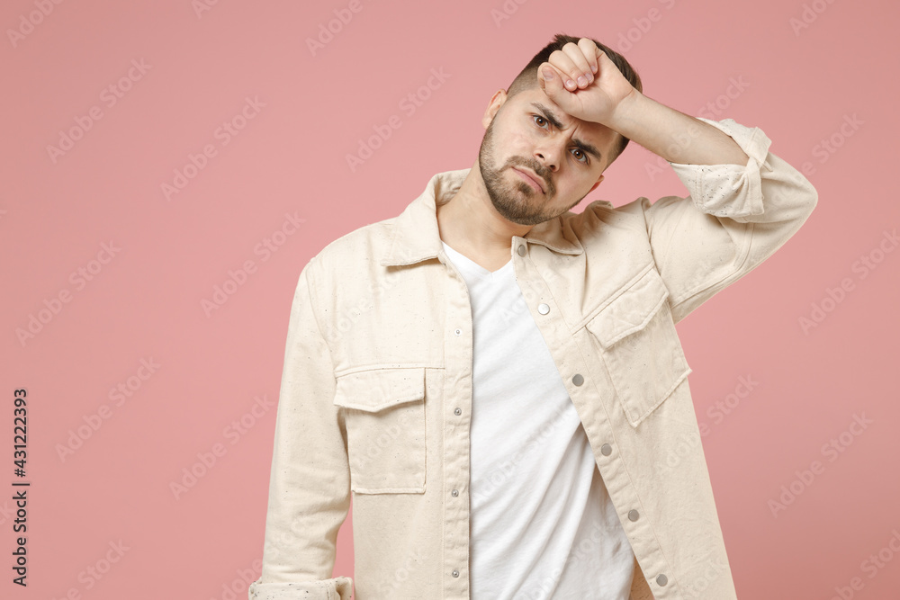 Young troubled sick ill pensive thoughtful sad man 20s in jacket white t-shirt put hand on forehead have headache migraine isolated on pastel pink background studio portrait People lifestyle concept Young troubled sick ill pensive thoughtful sad man 20s in jacket white t-shirt put hand on forehead have headache migraine isolated on pastel pink background studio portrait People lifestyle concept