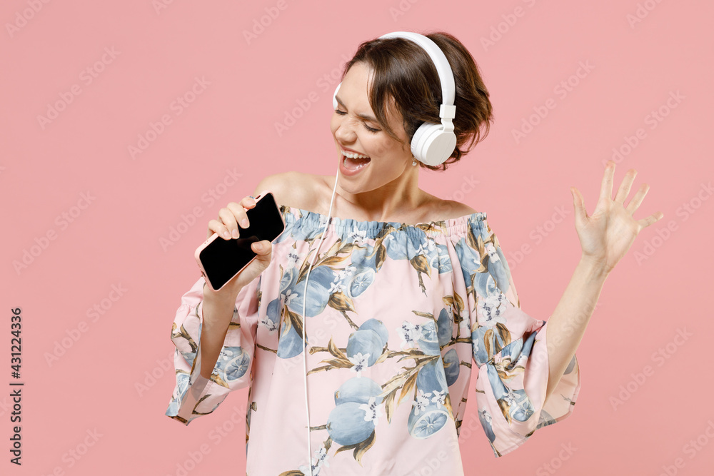 Young caucasian woman with short hairdo wear trendy stylish blouse headphones listen to music dancing sing song record voice by mobile cell phone dictaphone isolated on pastel pink background studio Young caucasian woman with short hairdo wear trendy stylish blouse headphones listen to music dancing sing song record voice by mobile cell phone dictaphone isolated on pastel pink background studio