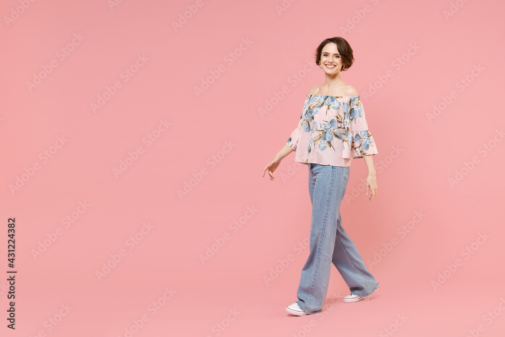 Full length young happy smiling fun caucasian woman 20s with short hairdo wear trendy stylish blouse walking going isolated on pastel pink background studio portrait. People lifestyle fashion concept Full length young happy smiling fun caucasian woman 20s with short hairdo wear trendy stylish blouse walking going isolated on pastel pink background studio portrait. People lifestyle fashion concept