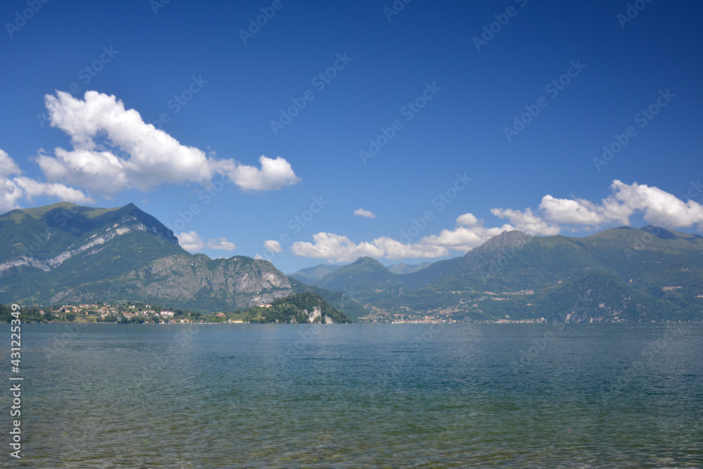 Horizontal panorama of fresh lake Como surrounded by hills covered with green cedar forest Italy Lierna, June 23 2018.