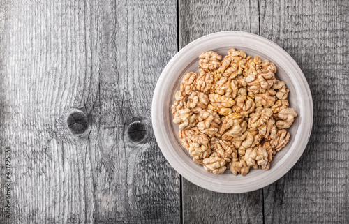 Walnuts in peel ready to eat kitchen table arrangement on gray plate overhead with copy space studio shot