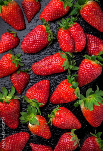 Strawberries vibrant color overhead close up arrangement on black shiny kitchen table ready to eat studio shot
