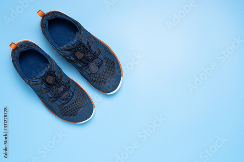 Pair of blue children sport sneakers or shoes on blue background, top view.