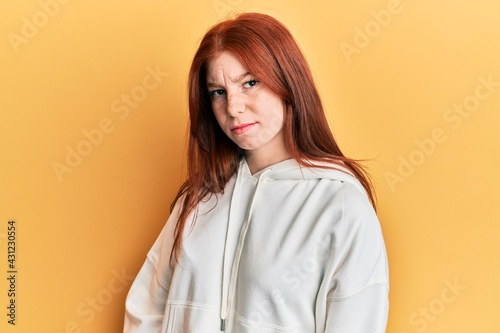 Young red head girl wearing casual sweatshirt skeptic and nervous, frowning upset because of problem. negative person.
