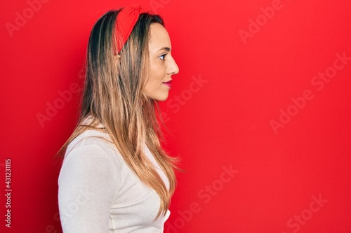 Beautiful hispanic woman wearing red diadem looking to side, relax profile pose with natural face with confident smile.