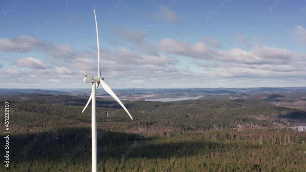 AERIAL - A wind turbine in a forest wind energy farm, Sweden, wide spinning shot