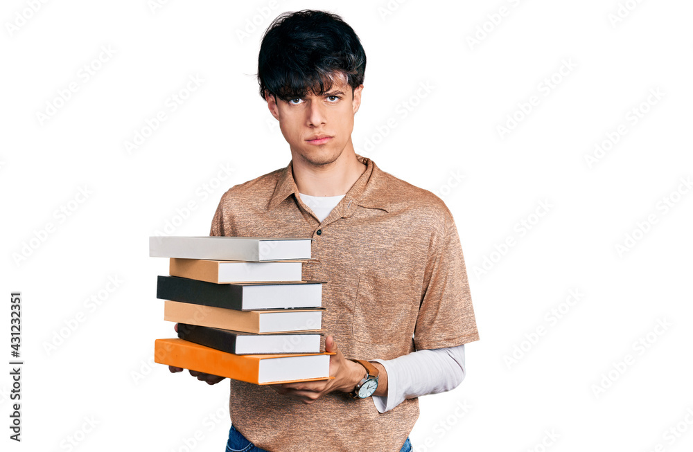 Handsome hipster young man holding a pile of books skeptic and nervous, frowning upset because of problem. negative person. Handsome hipster young man holding a pile of books skeptic and nervous, frowning upset because of problem. negative person.