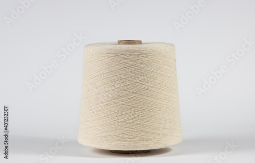 Large bobbin of light thread on white isolated background with even winding