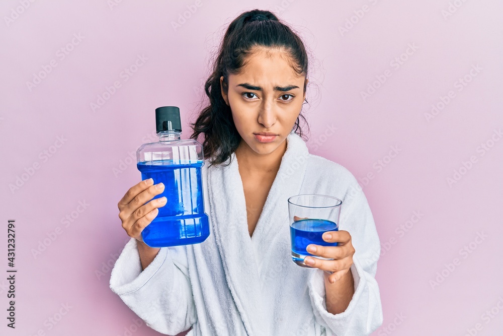 Hispanic teenager girl with dental braces holding mouthwash depressed and worry for distress, crying angry and afraid. sad expression. Hispanic teenager girl with dental braces holding mouthwash depressed and worry for distress, crying angry and afraid. sad expression.