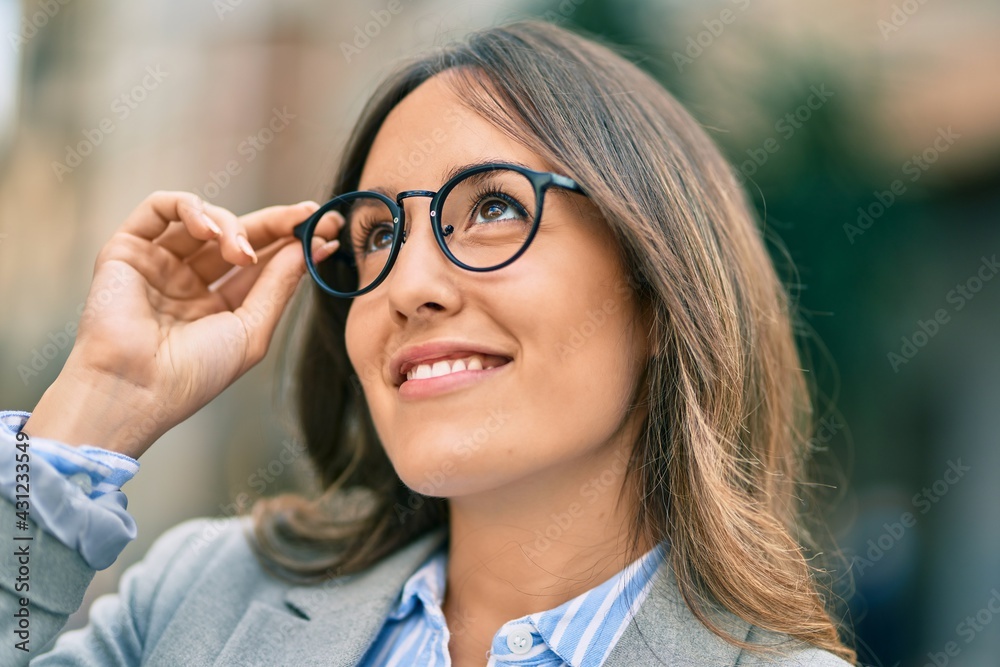Young hispanic businesswoman smiling happy touching her glasses at the city. Young hispanic businesswoman smiling happy touching her glasses at the city.