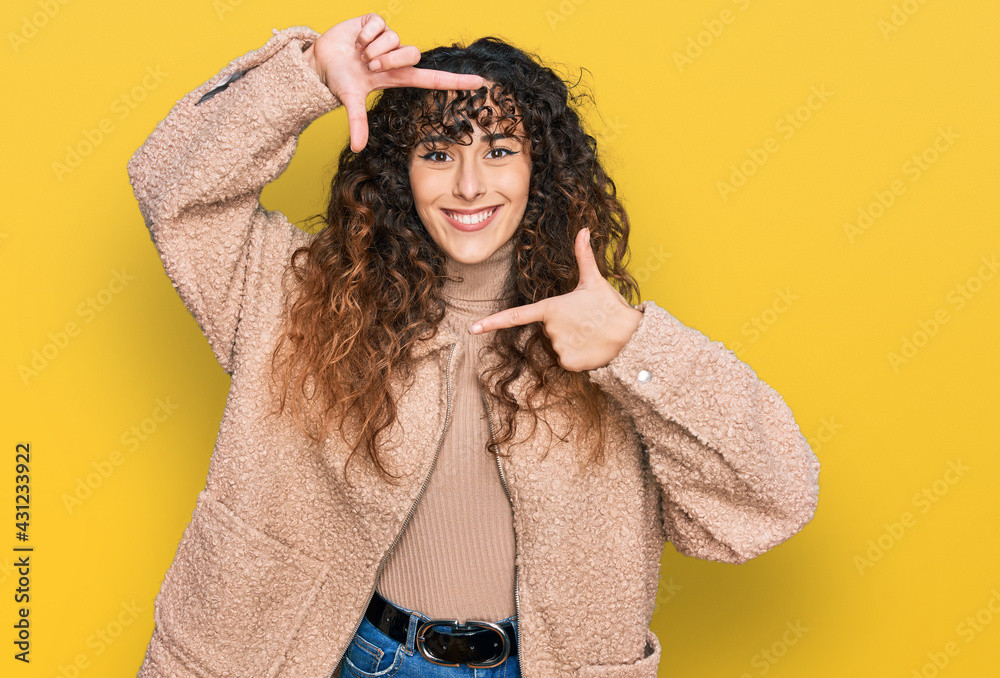 Young hispanic girl wearing winter clothes smiling making frame with hands and fingers with happy face. creativity and photography concept. Young hispanic girl wearing winter clothes smiling making frame with hands and fingers with happy face. creativity and photography concept.