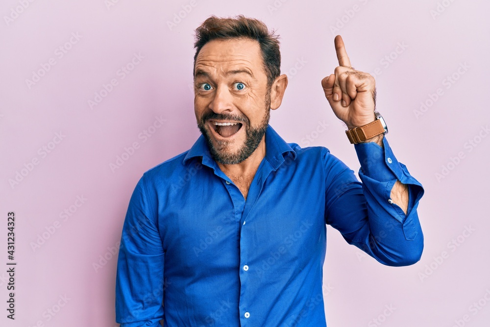 Middle age man wearing casual clothes pointing finger up with successful idea. exited and happy. number one. Middle age man wearing casual clothes pointing finger up with successful idea. exited and happy. number one.