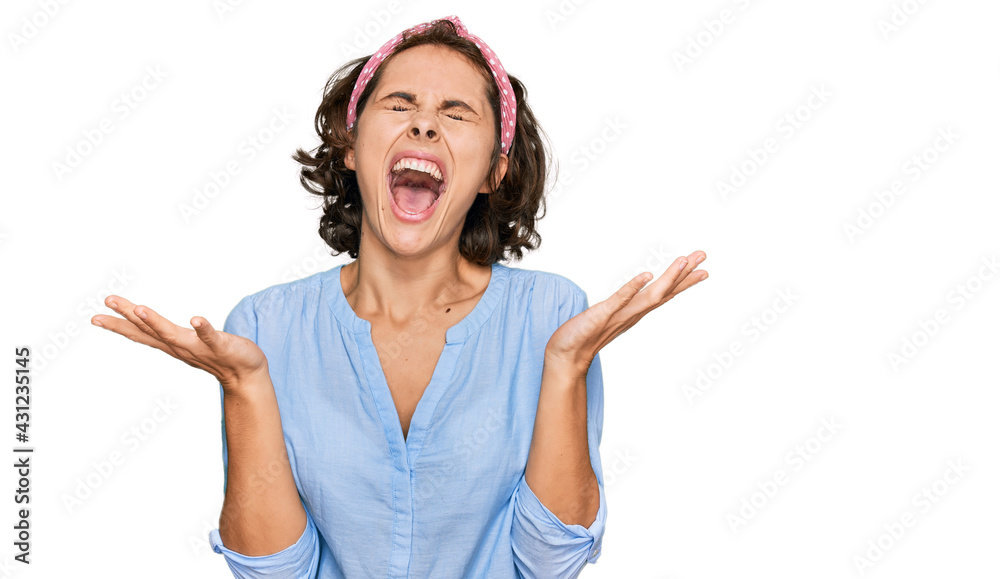Young hispanic woman wearing casual clothes celebrating mad and crazy for success with arms raised and closed eyes screaming excited. winner concept Young hispanic woman wearing casual clothes celebrating mad and crazy for success with arms raised and closed eyes screaming excited. winner concept