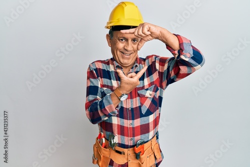 Senior hispanic man wearing handyman uniform smiling making frame with hands and fingers with happy face. creativity and photography concept.
