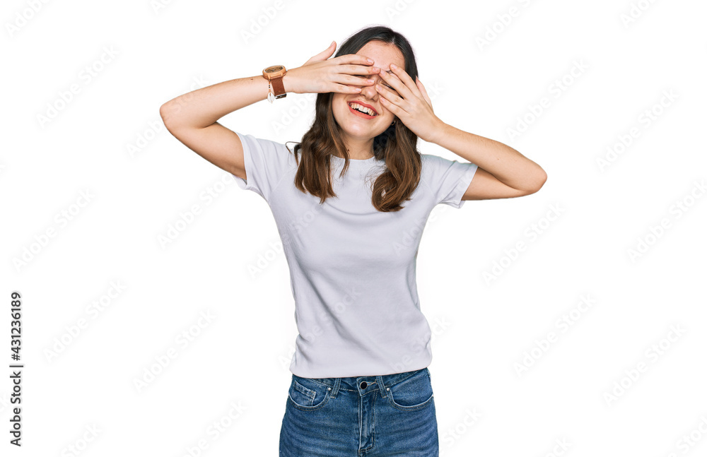 Young beautiful woman wearing casual white t shirt covering eyes with hands smiling cheerful and funny. blind concept. Young beautiful woman wearing casual white t shirt covering eyes with hands smiling cheerful and funny. blind concept.