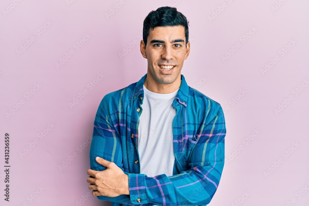 Handsome hispanic man wearing casual clothes happy face smiling with crossed arms looking at the camera. positive person.