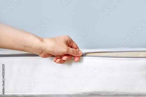 Orthopedic mattress with removable cover. Hand unzips the zipper close-up. Copy space