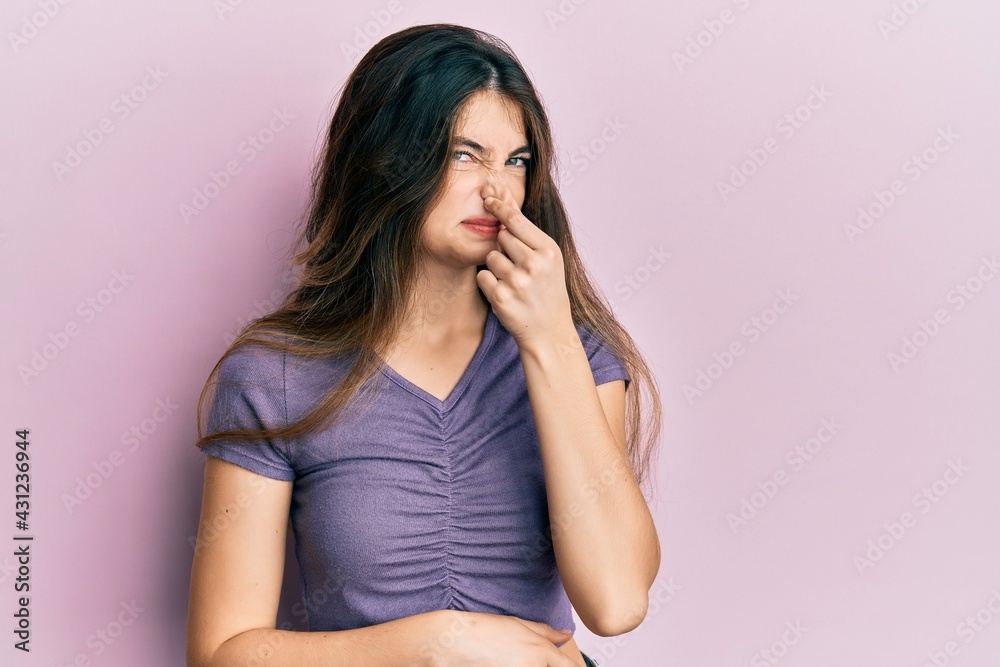 Young caucasian woman wearing casual clothes smelling something stinky and disgusting, intolerable smell, holding breath with fingers on nose. bad smell Young caucasian woman wearing casual clothes smelling something stinky and disgusting, intolerable smell, holding breath with fingers on nose. bad smell