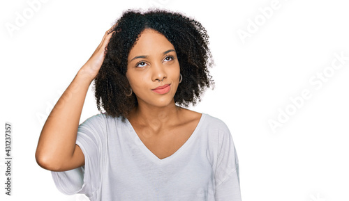 Young african american girl wearing casual clothes confuse and wonder about question. uncertain with doubt  thinking with hand on head. pensive concept.