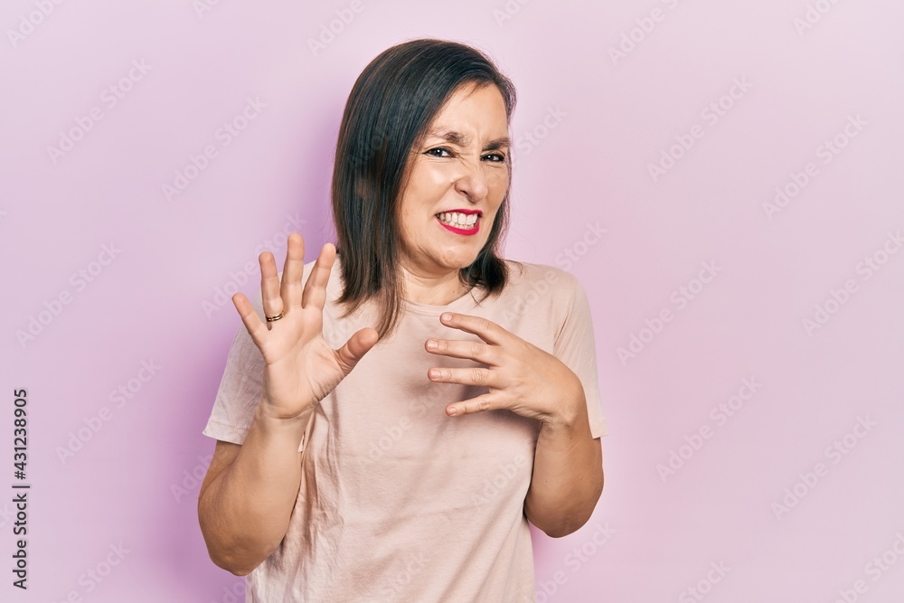 Middle age hispanic woman wearing casual clothes disgusted expression, displeased and fearful doing disgust face because aversion reaction. with hands raised Middle age hispanic woman wearing casual clothes disgusted expression, displeased and fearful doing disgust face because aversion reaction. with hands raised