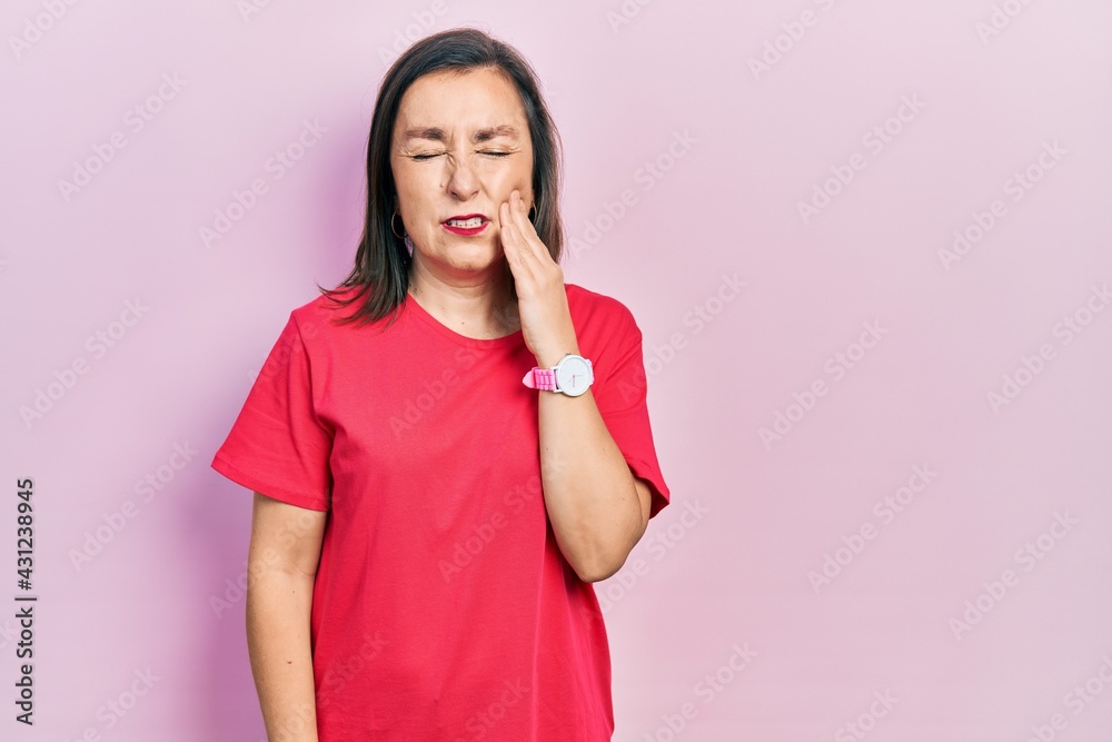 Middle age hispanic woman wearing casual clothes touching mouth with hand with painful expression because of toothache or dental illness on teeth. dentist Middle age hispanic woman wearing casual clothes touching mouth with hand with painful expression because of toothache or dental illness on teeth. dentist